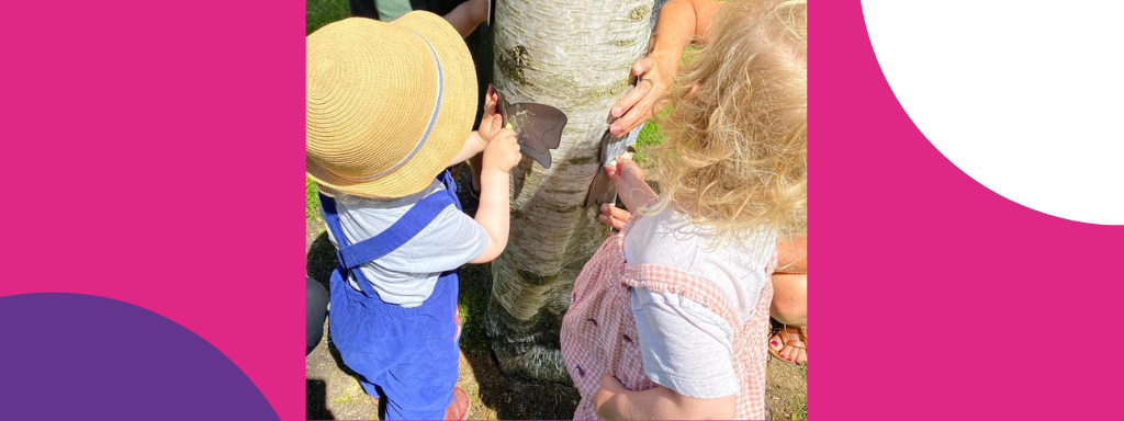 Two toddlers enjoying nature art, doing a bark rubbing on a tree