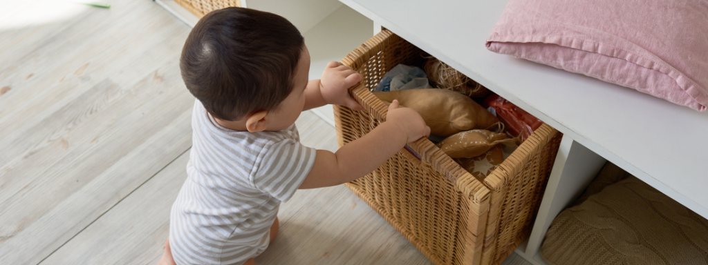 home organisation tips for parents - photo shows a toddler pulling out a container full of soft textiles including cushions and items for the living room