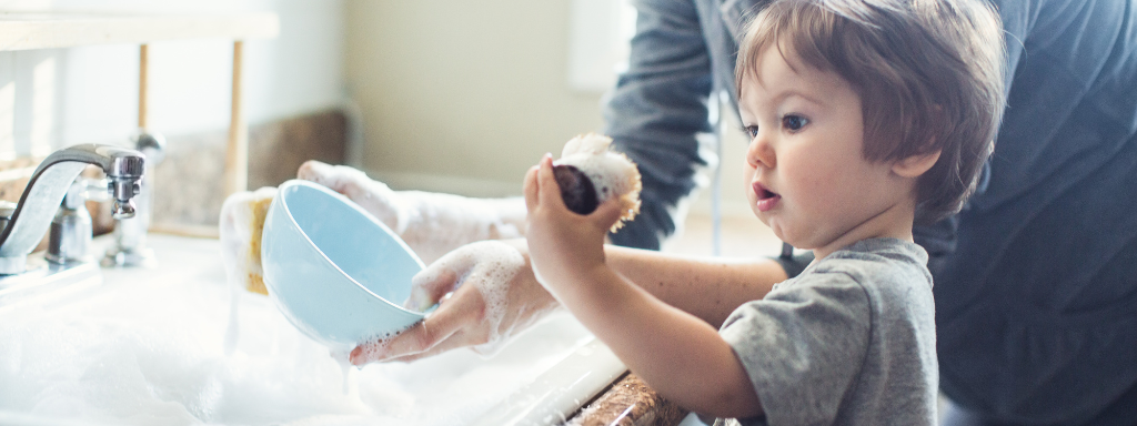 chores for under fives - the photo shows a child helping to wash up