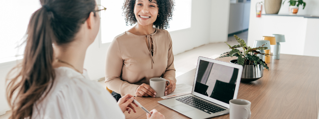 maternity leave checklist - the photo shows two women in an office having a chat over a cup of tea