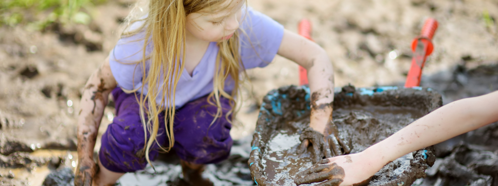 play for early childhood development - the photo shows a child putting their hand in mud in a wheelbarrow