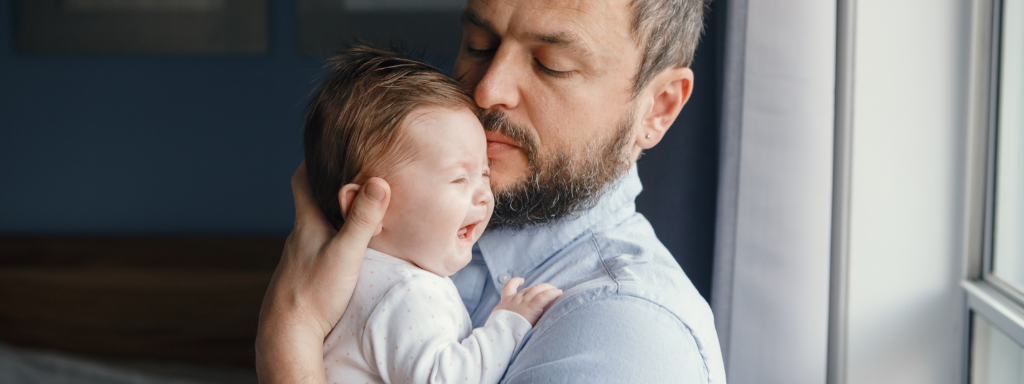 new father nighttime duties - the photo shows a dad holding a crying baby